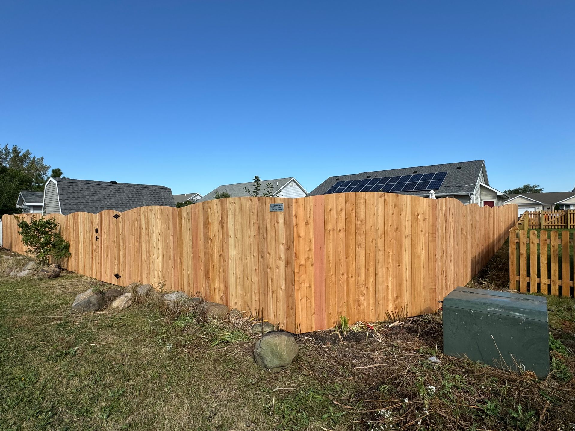 Wooden fence in a yard with a blue sky.
