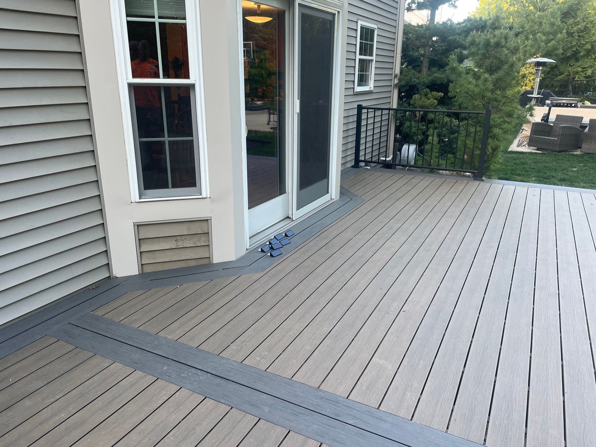 Composite deck with sliding glass door and window on a house exterior.