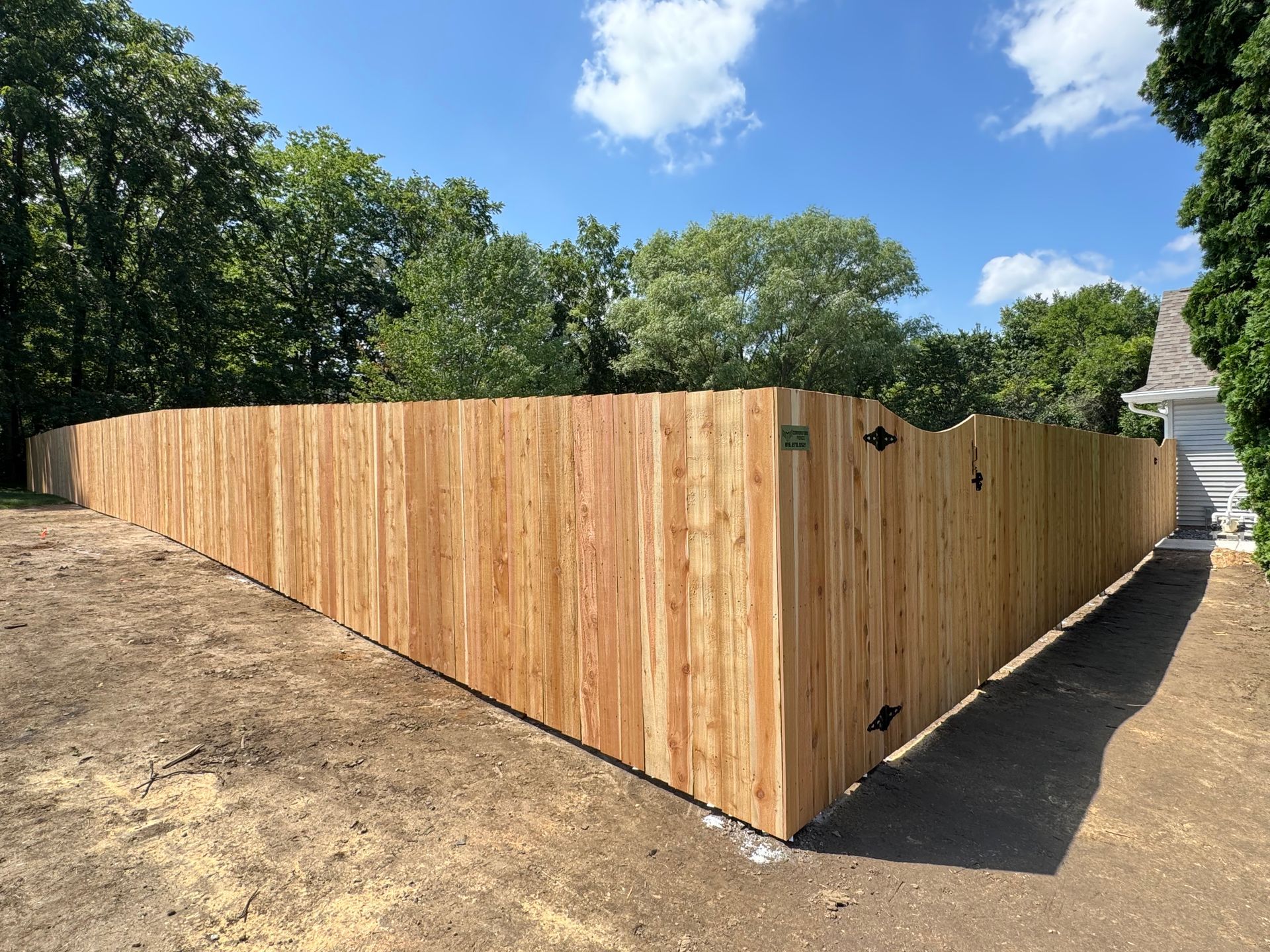 Wooden fence enclosing a yard on a sunny day.