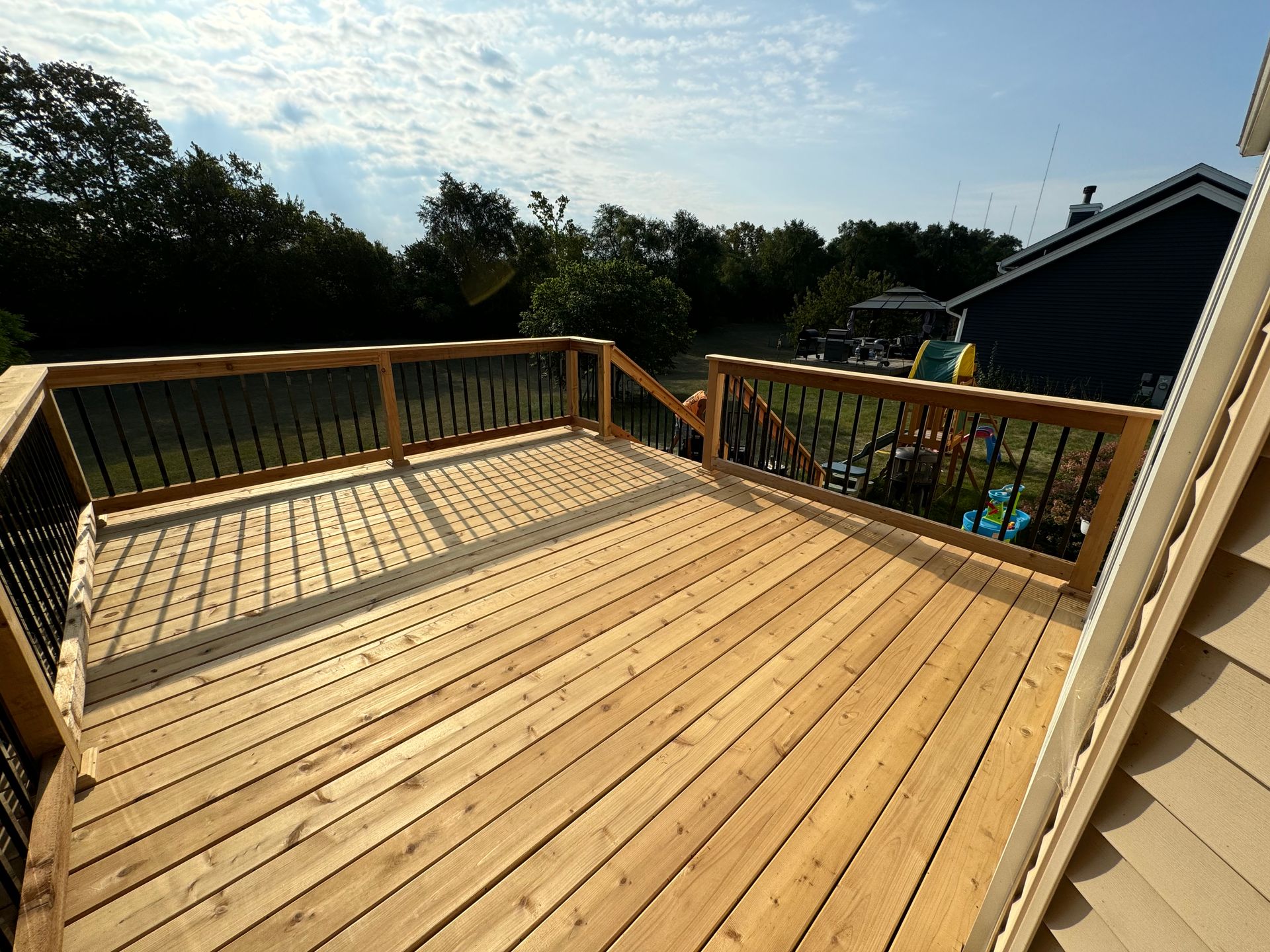 Wooden deck with black railings on a sunny day.