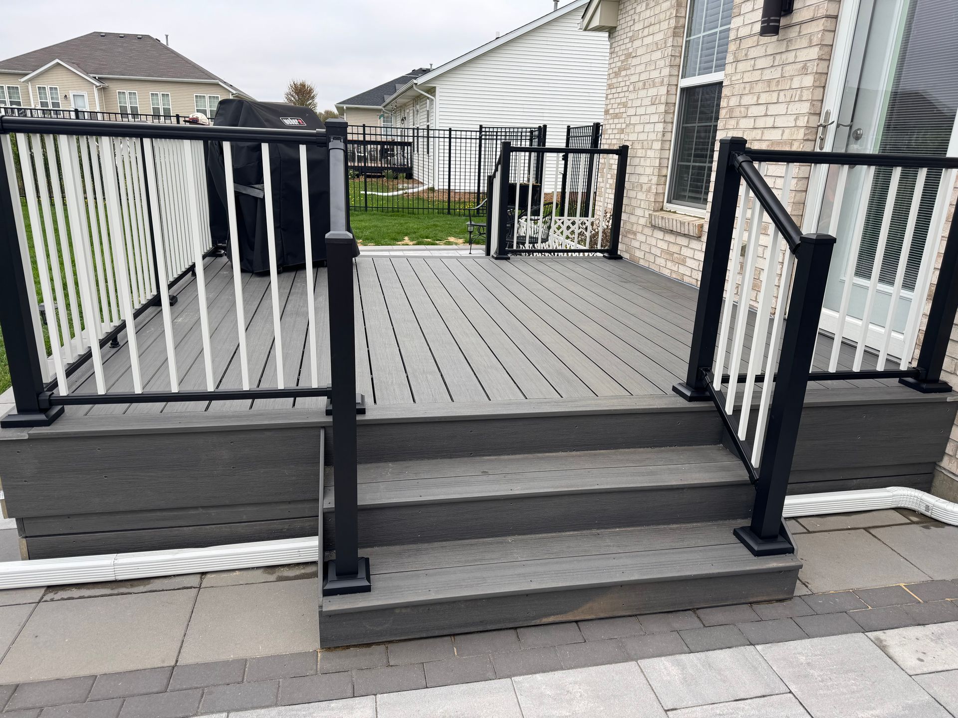 Gray composite deck with black and white railing and steps.