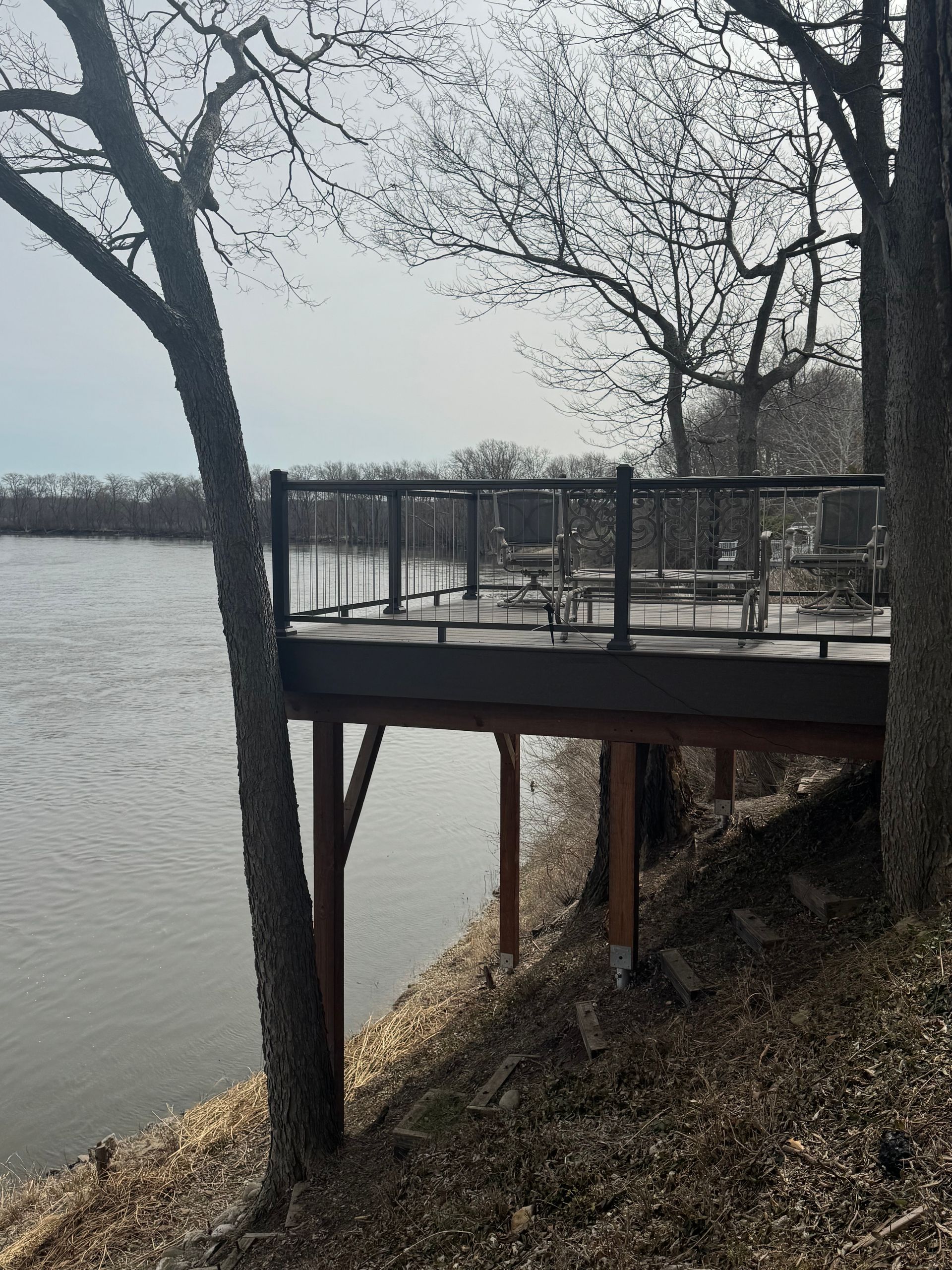 Deck overlooking a body of water with trees in the foreground.