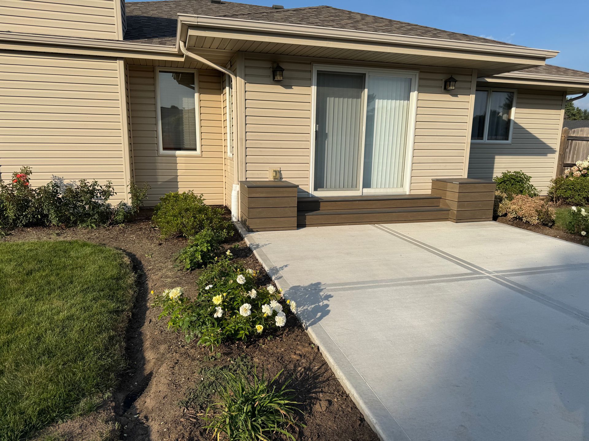 Beige house exterior with a patio and landscaping. Sliding glass door and small step.