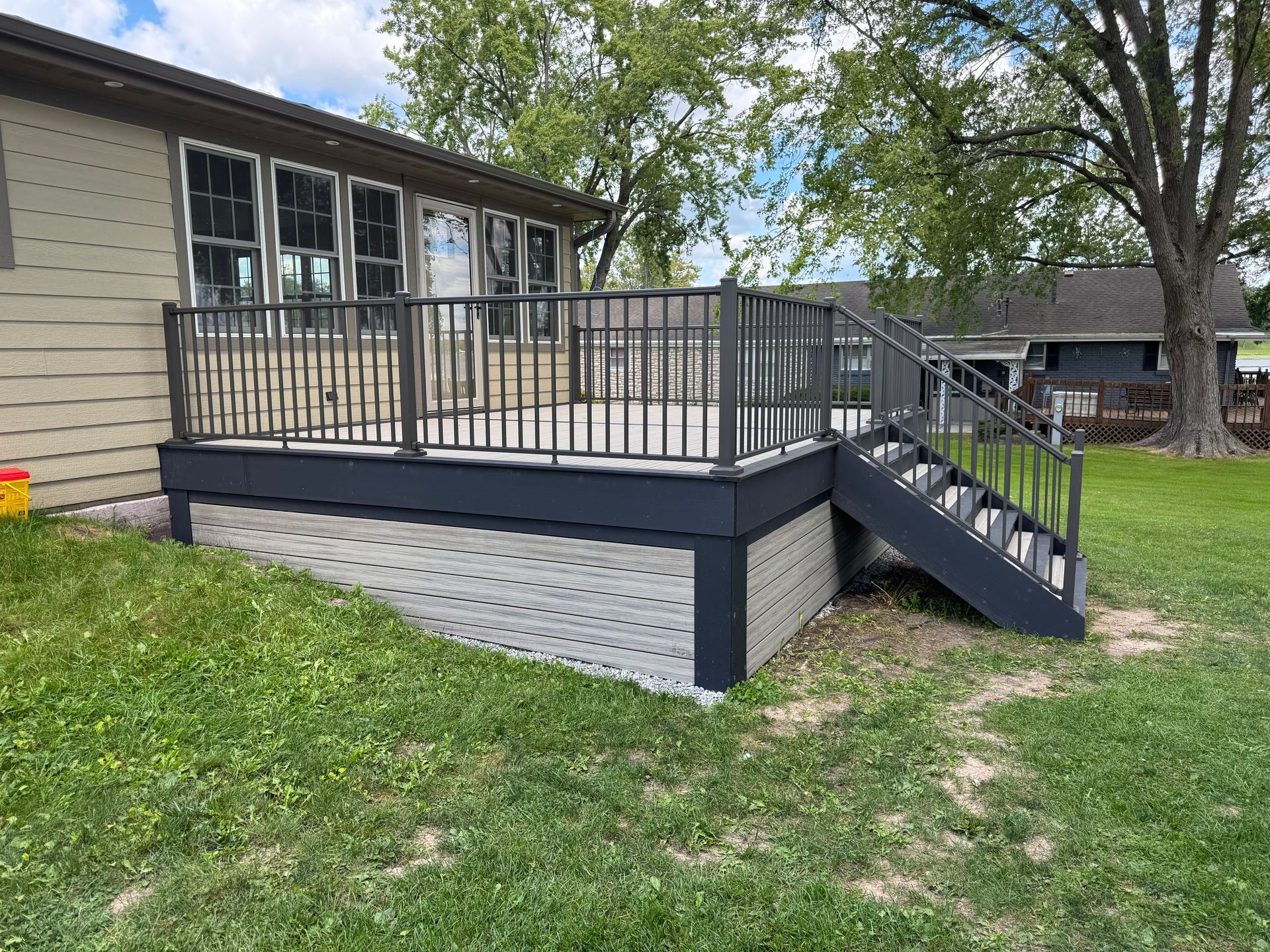A raised deck with black railings and stairs, attached to a light brown building.