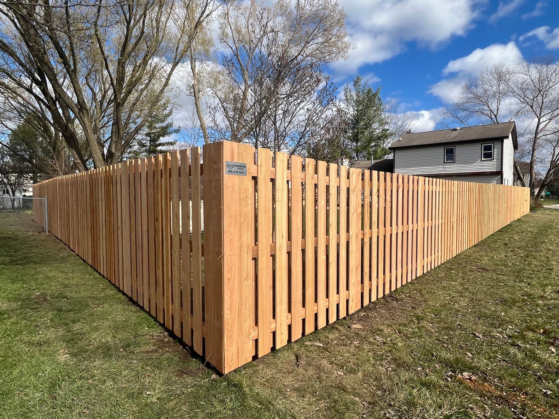Wooden privacy fence corner in a yard, sunny day.