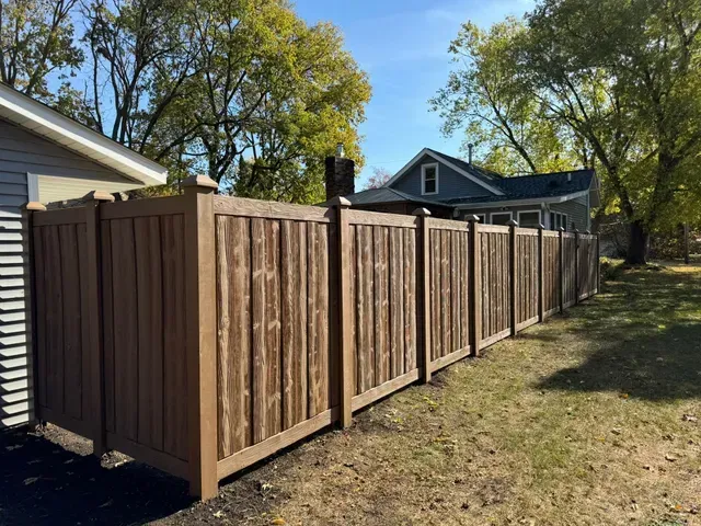 Brown wooden privacy fence in a yard on a sunny day.