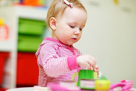 A little girl is sitting at a table playing with toys