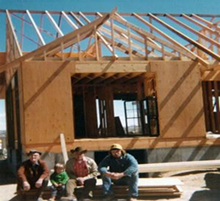 A group of people sitting in front of a house under construction