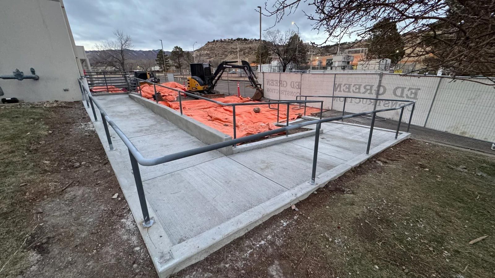 A concrete ramp with a metal railing is being built in front of a building.