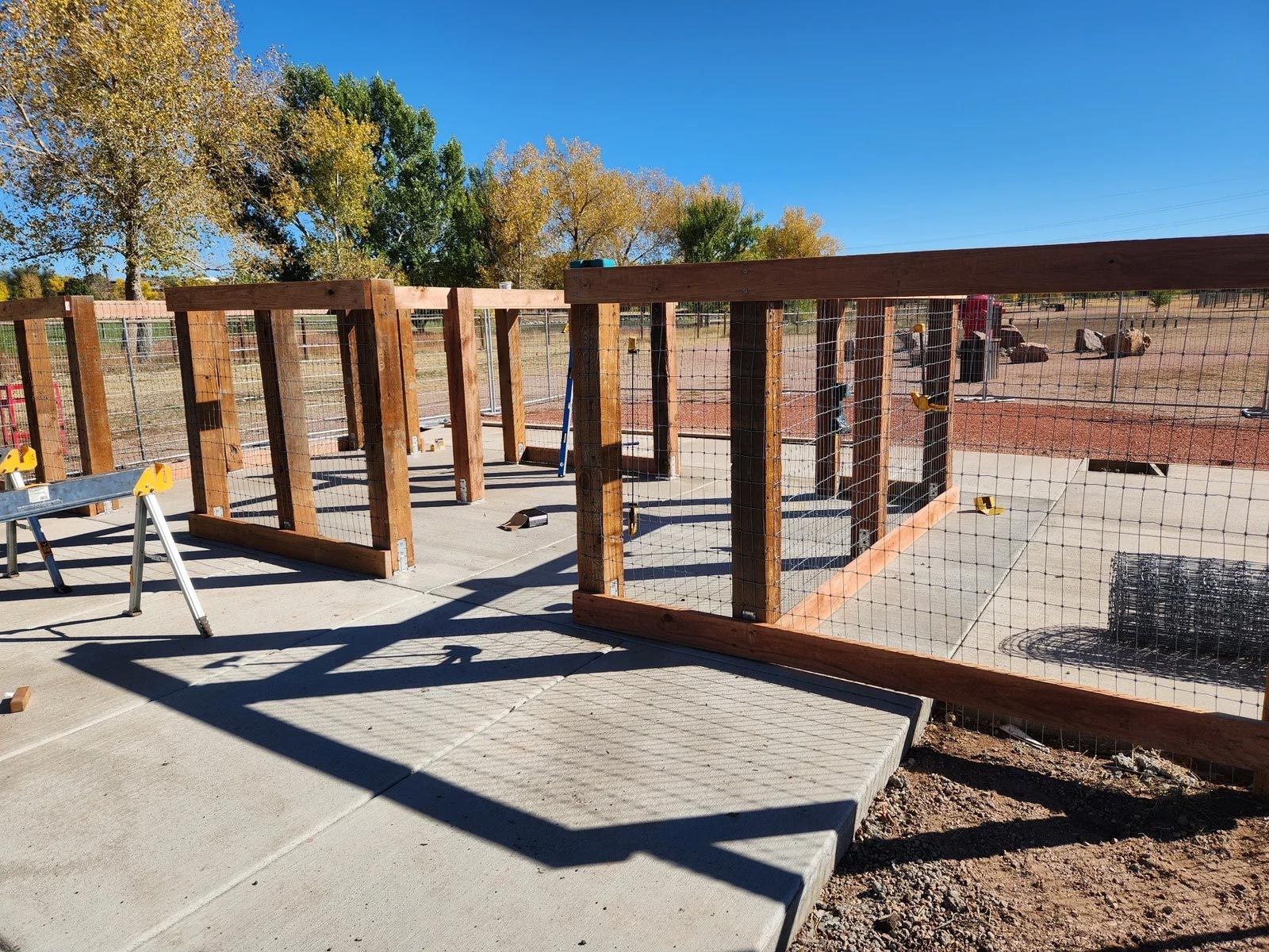 A wooden fence is being built on a concrete sidewalk.
