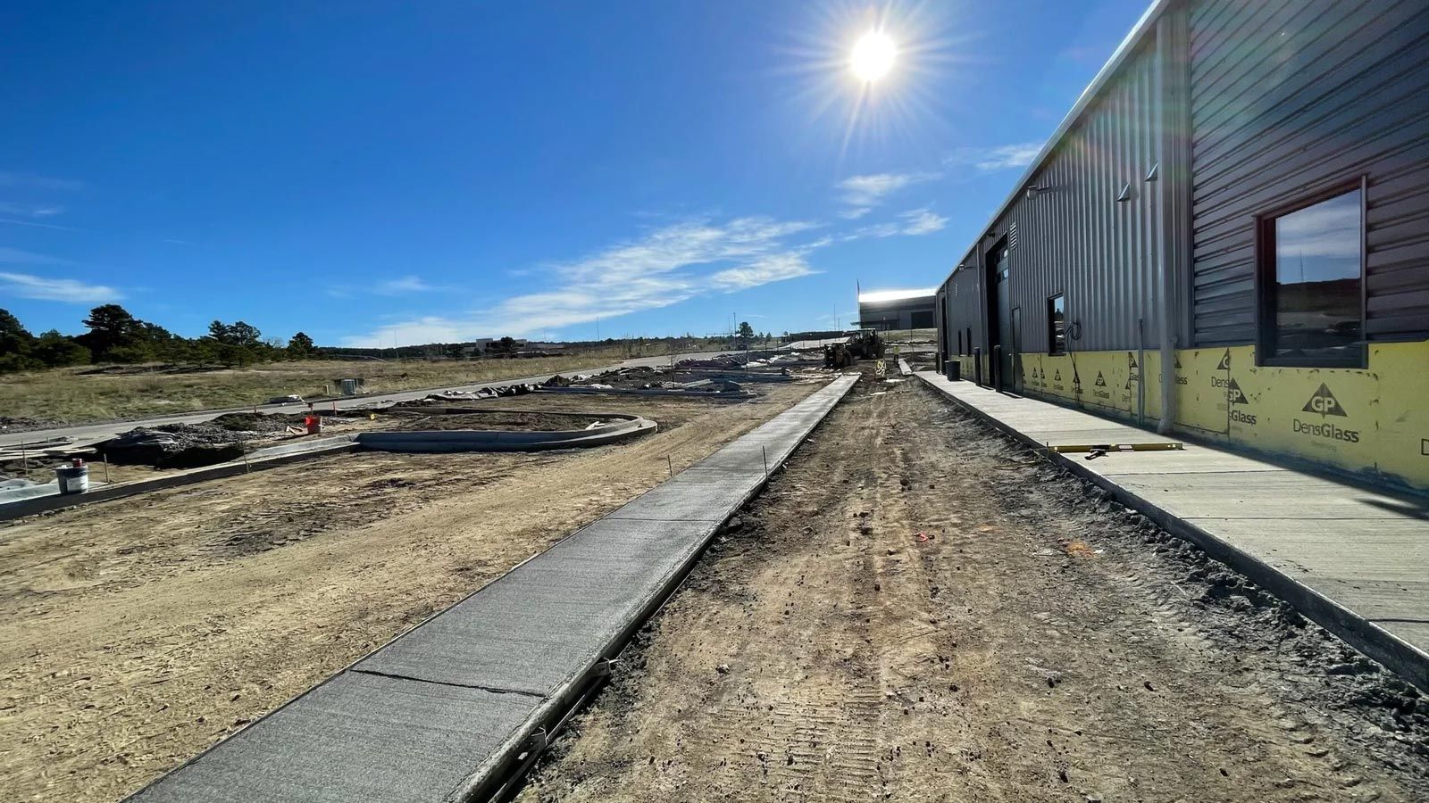 A dirt road leading to a building under construction.