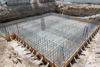 A concrete foundation is being built in a hole in the ground.