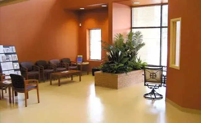 A waiting room with chairs a table and a plant