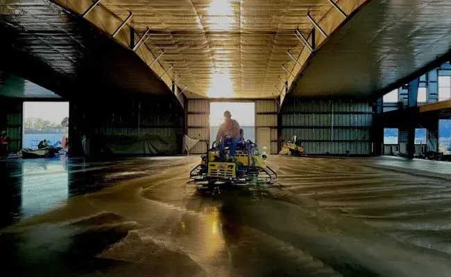 A man is driving a machine in a large warehouse.