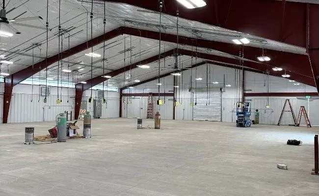 A large empty warehouse with a ceiling fan and a ladder.