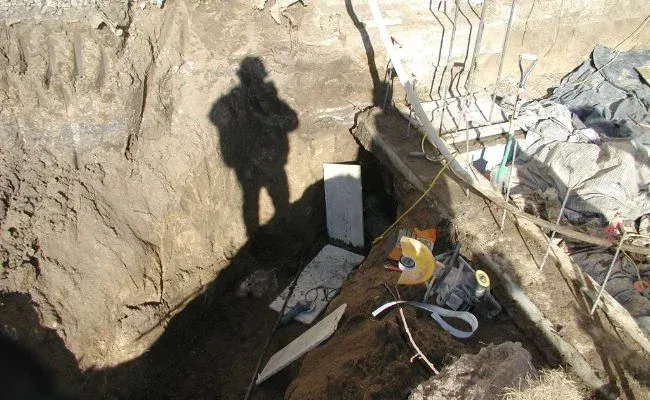 A shadow of a person is cast on a pile of dirt.