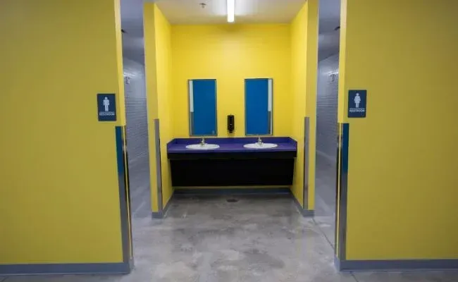 A bathroom with yellow walls and blue sinks