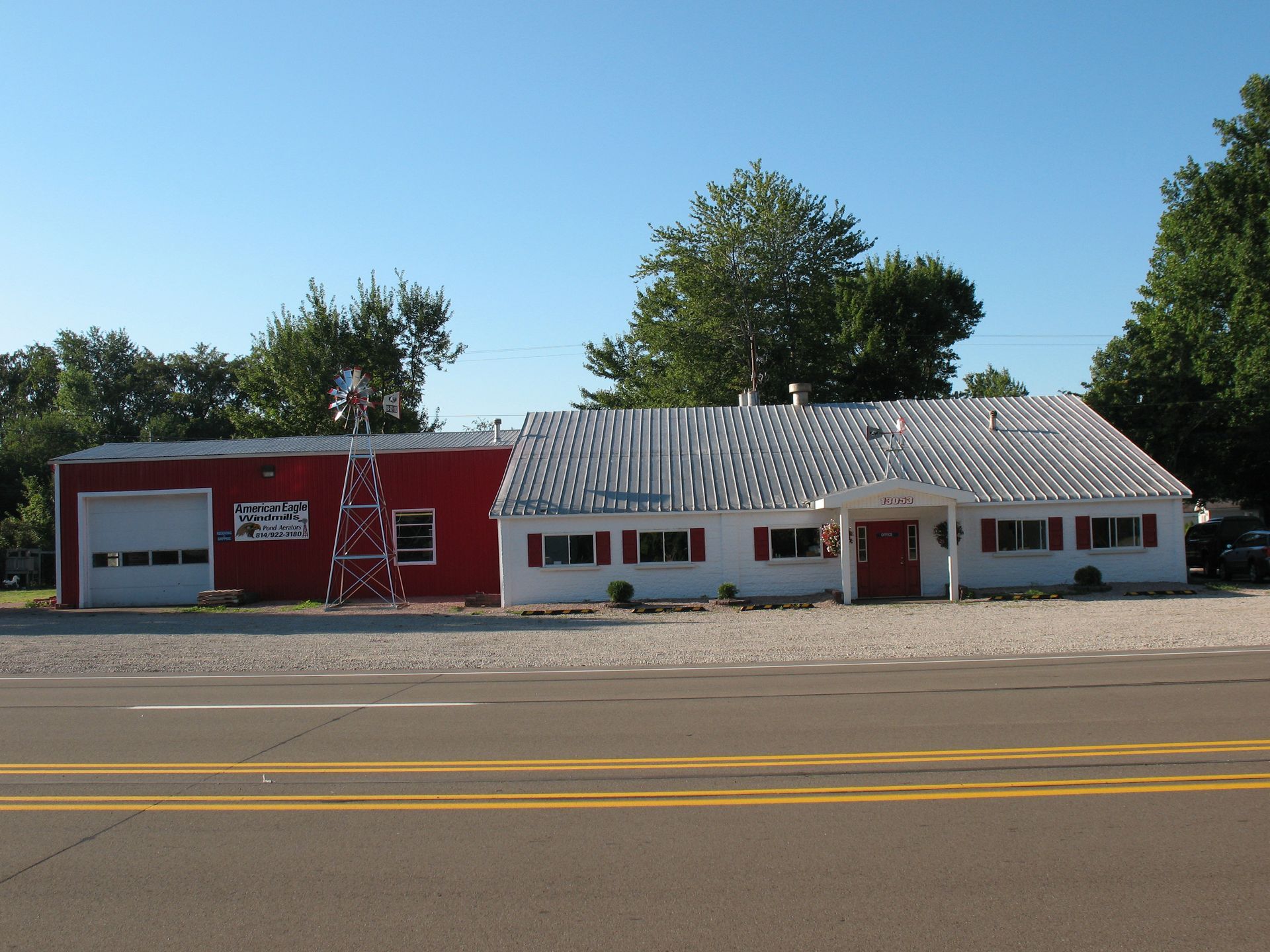 Red and white building with a garage door and sign, topped with a corrugated metal roof.