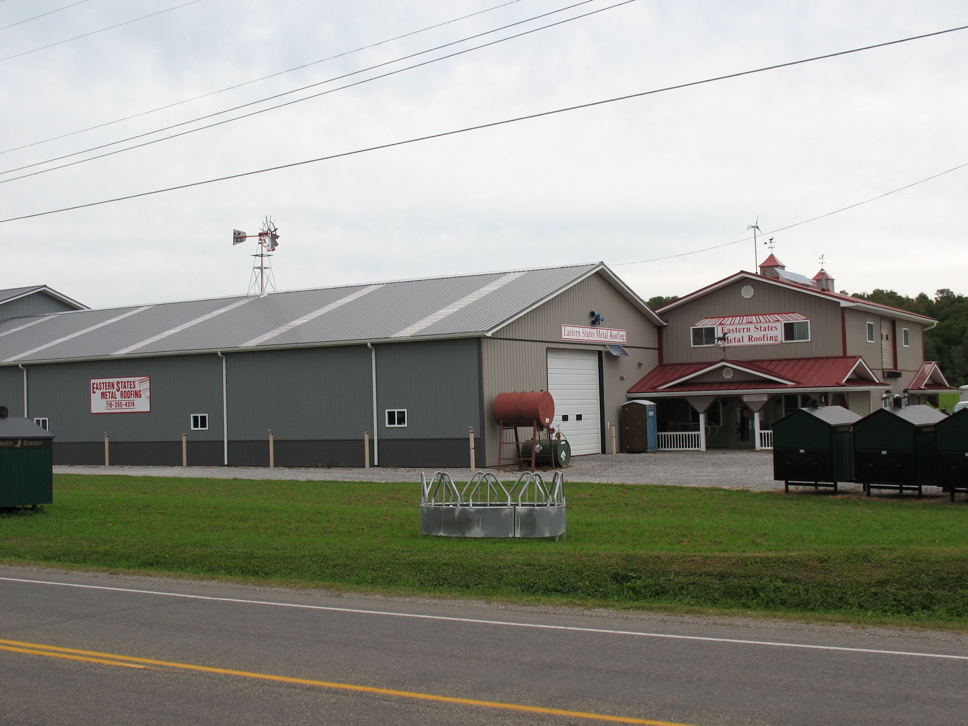 A farm building complex with a large gray warehouse and a smaller, ornate red-roofed structure.