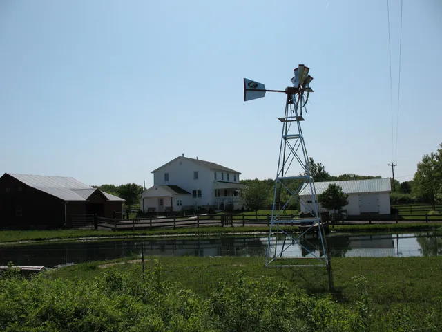 Farm scene with a white farmhouse, a red barn, and a water-pumping windmill.