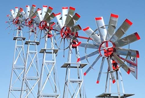 Several metal windmills with silver blades and red accents against a clear blue sky.