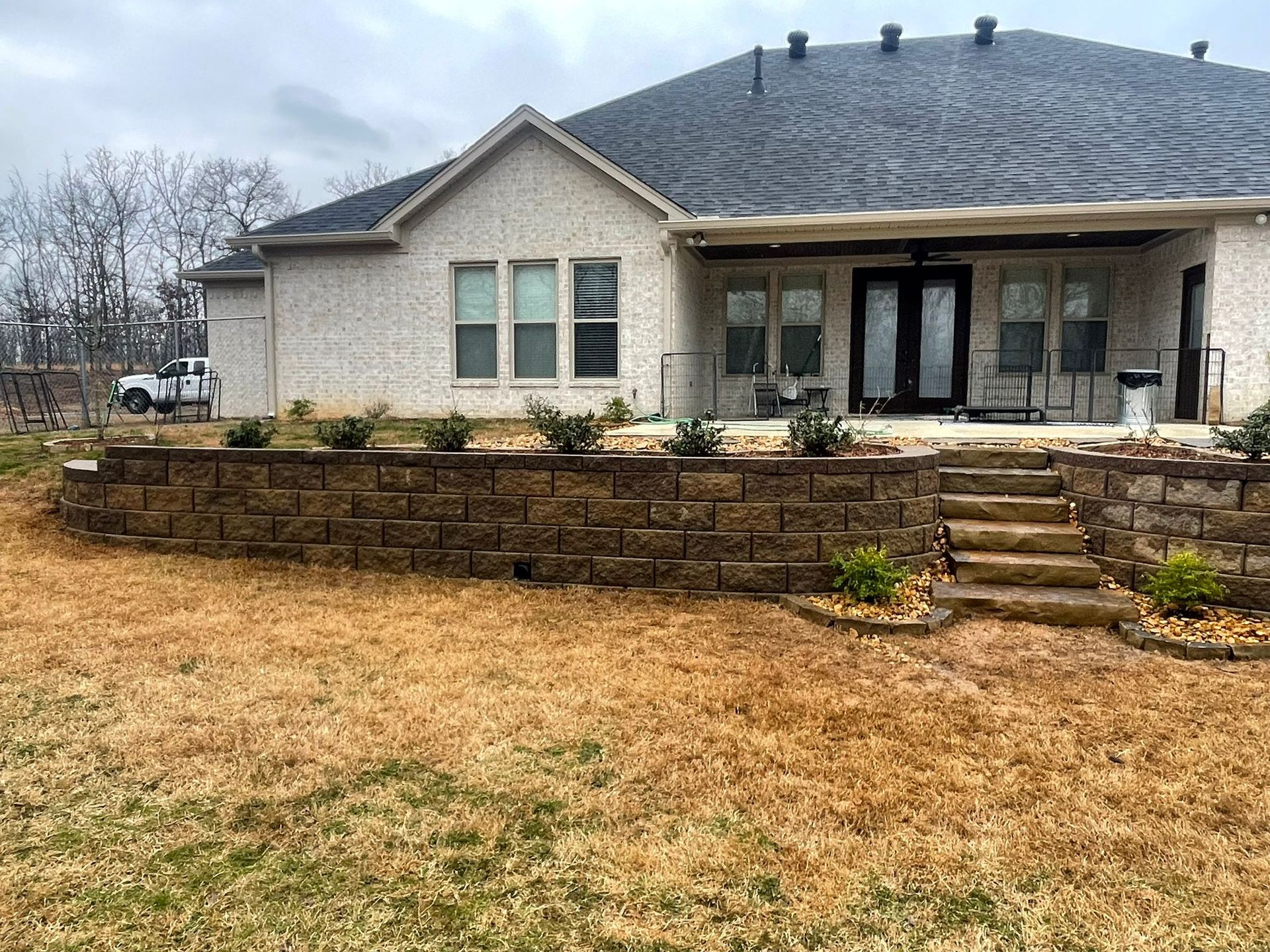 A house with a brick wall and stairs in front of it.