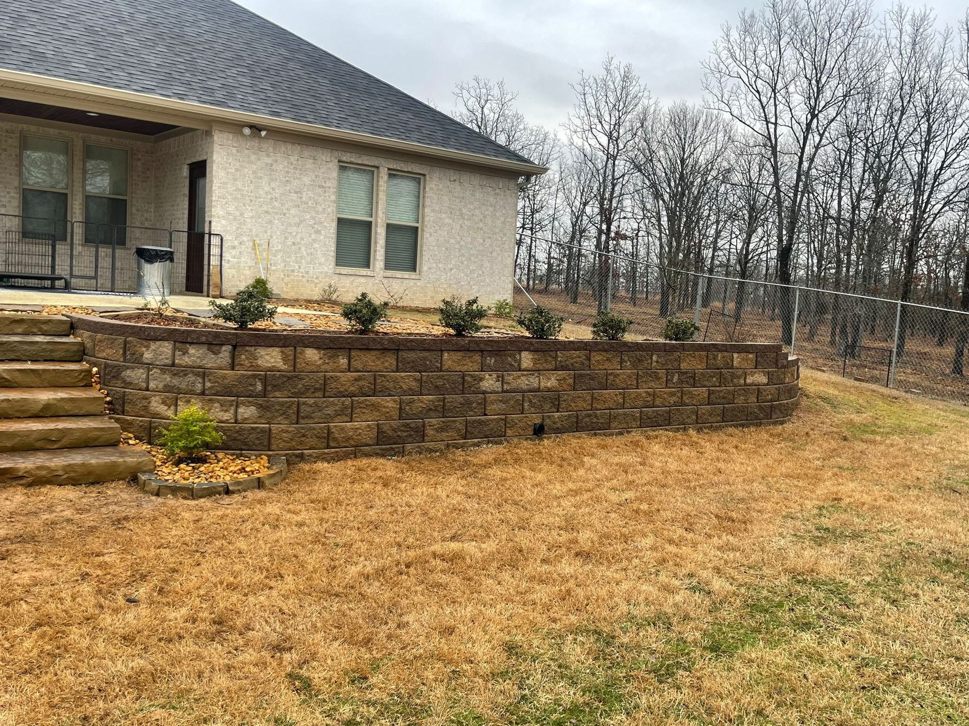 A house with a stone wall and stairs in front of it.