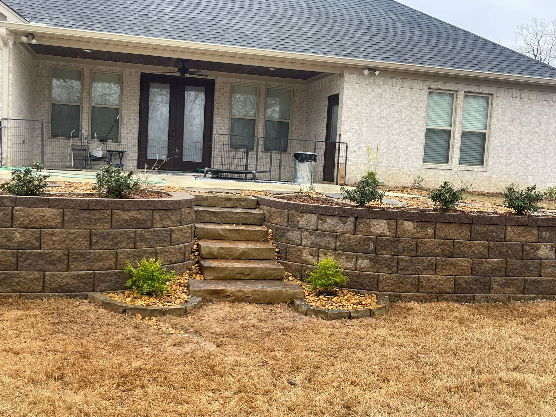 A white house with a brick wall and stairs in front of it.