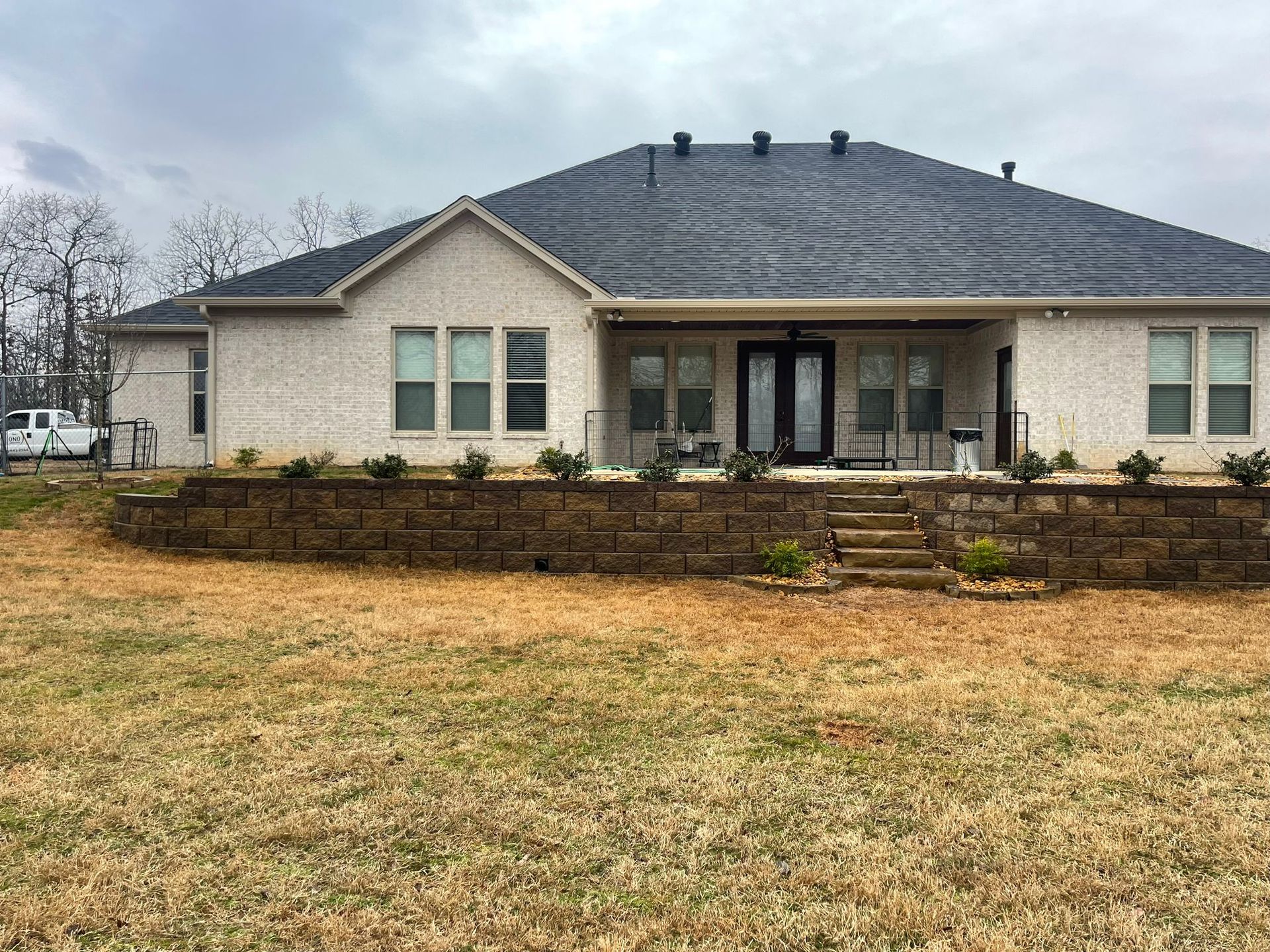A large white house with a black roof is sitting on top of a grassy hill.
