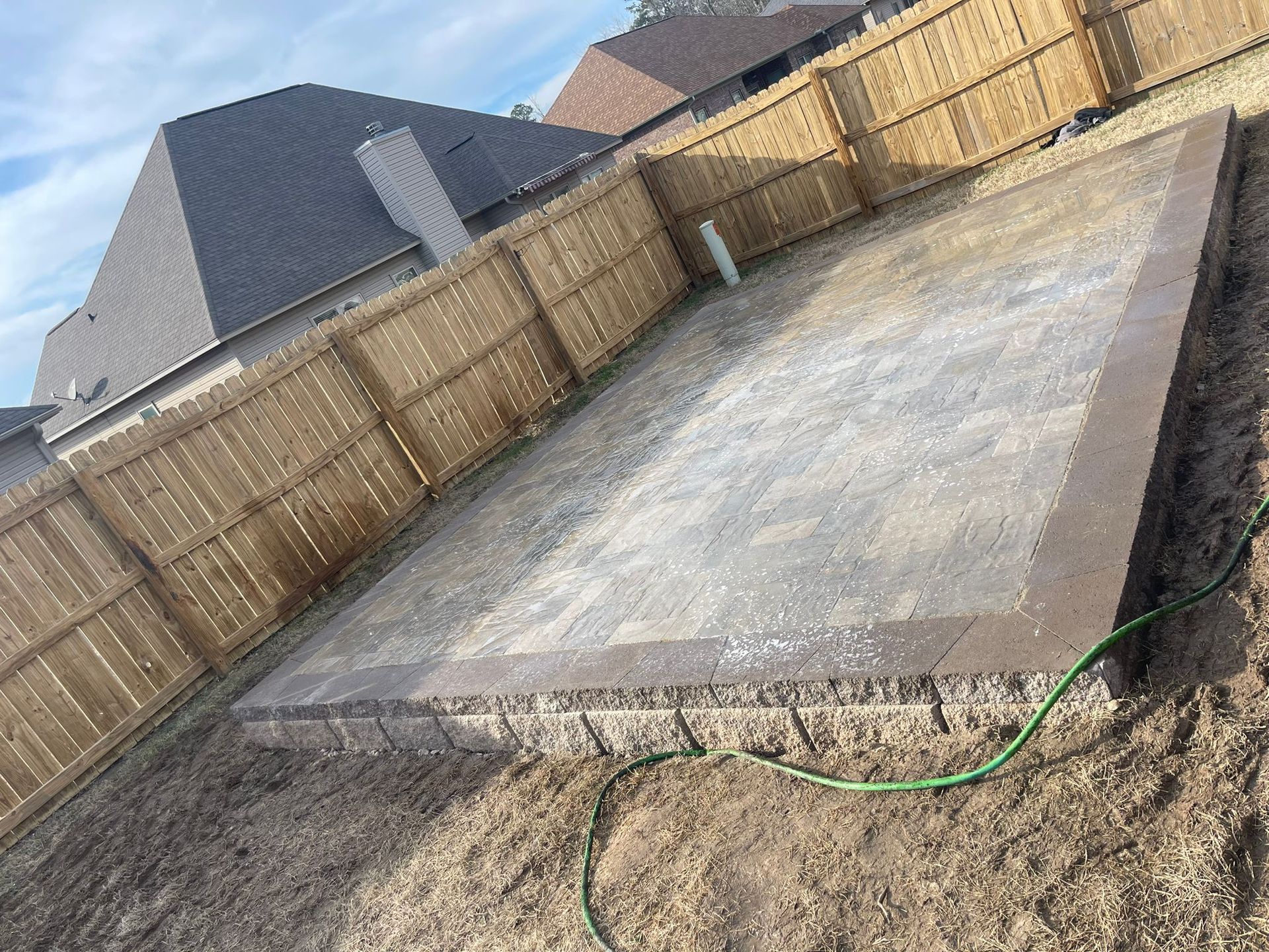 A concrete slab is sitting in the dirt in front of a wooden fence.