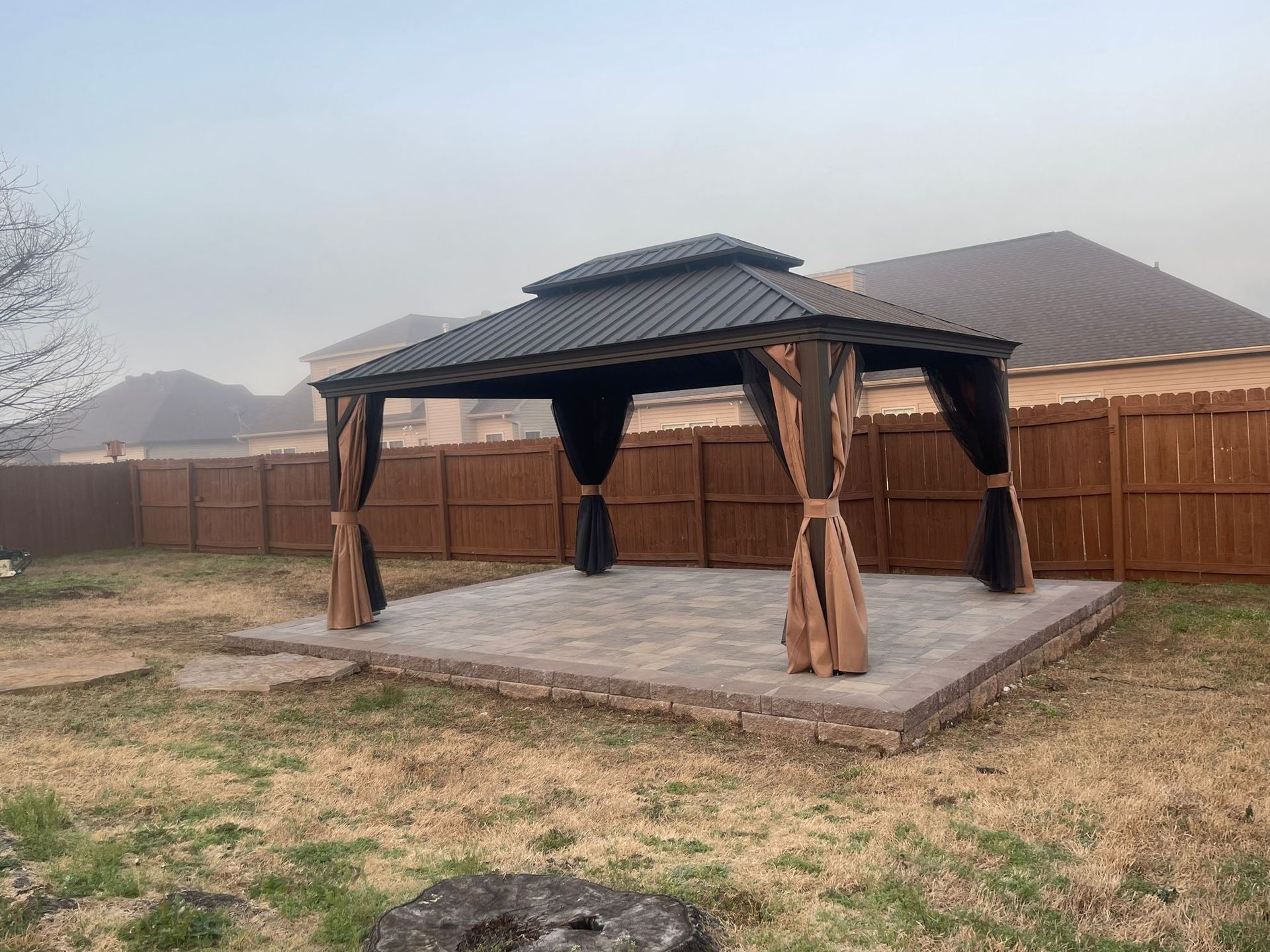 A gazebo in a backyard with a wooden fence in the background.