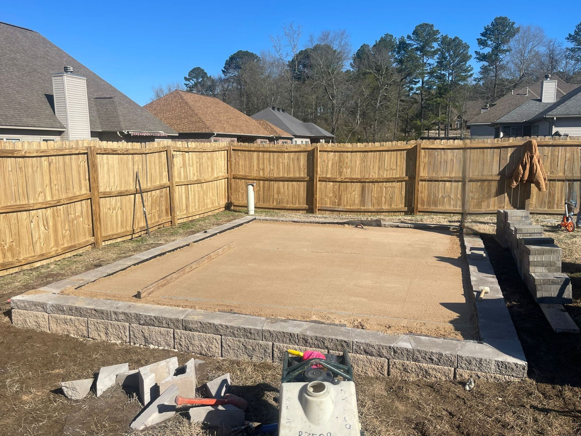 A backyard with a wooden fence and a lot of dirt.