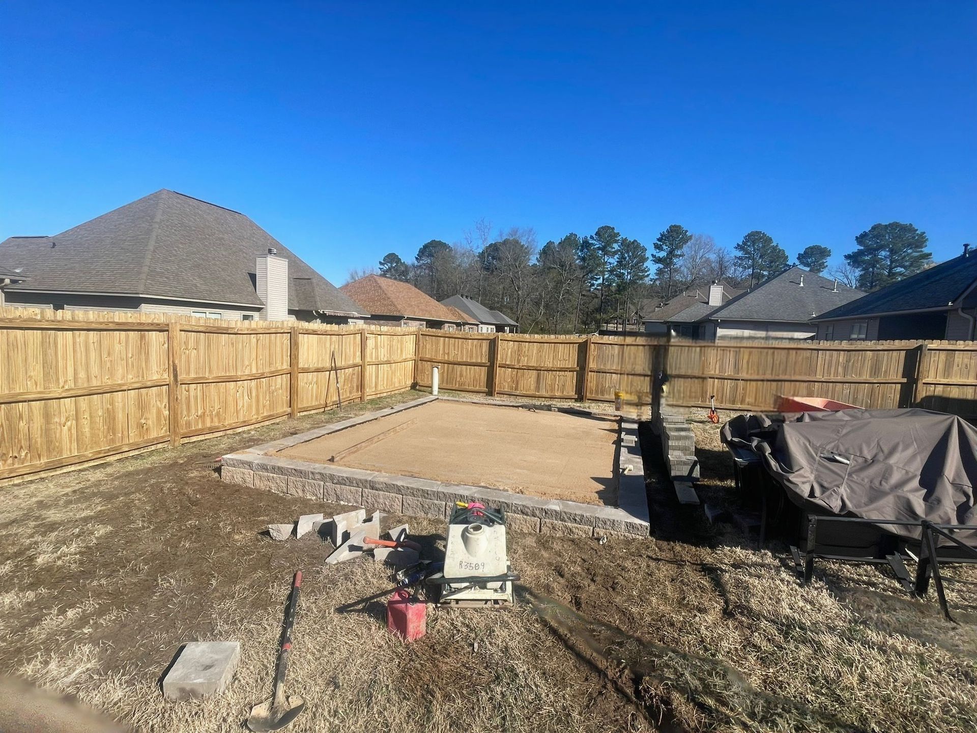 A backyard with a wooden fence and a lot of dirt.