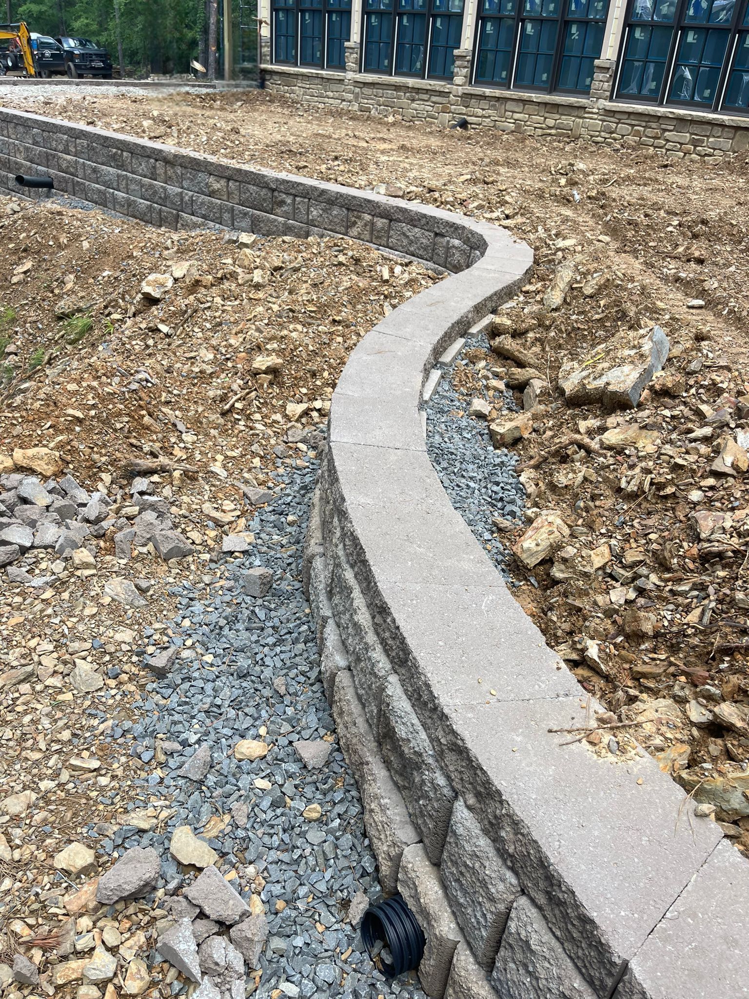 A stone wall is being built in the middle of a dirt field.
