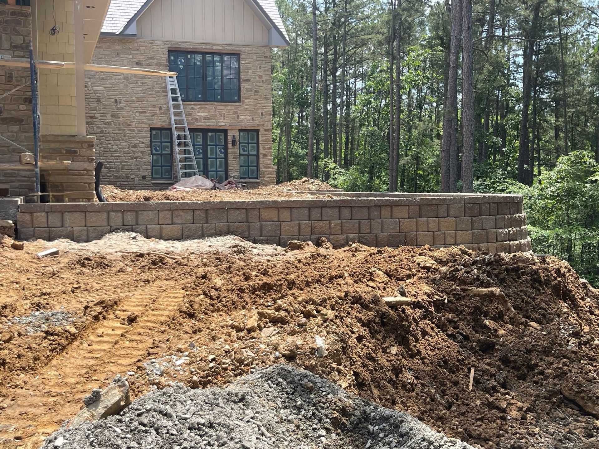A large brick house is being built in the middle of a dirt field.