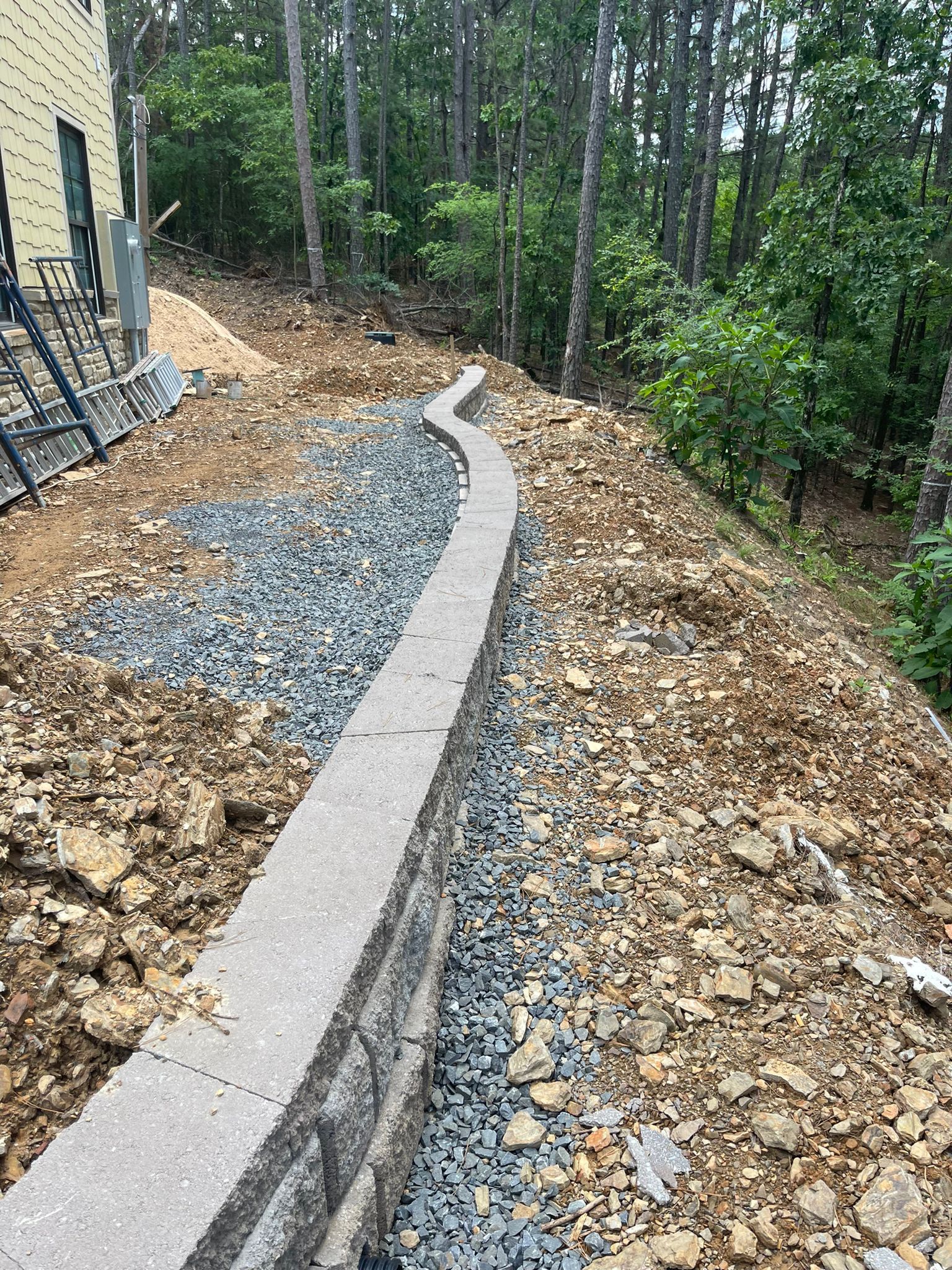 A concrete wall is being built on top of a rocky hill.
