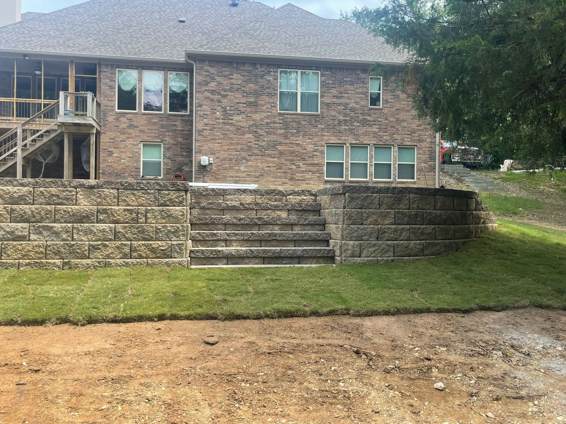 A large brick house with a stone wall in front of it.