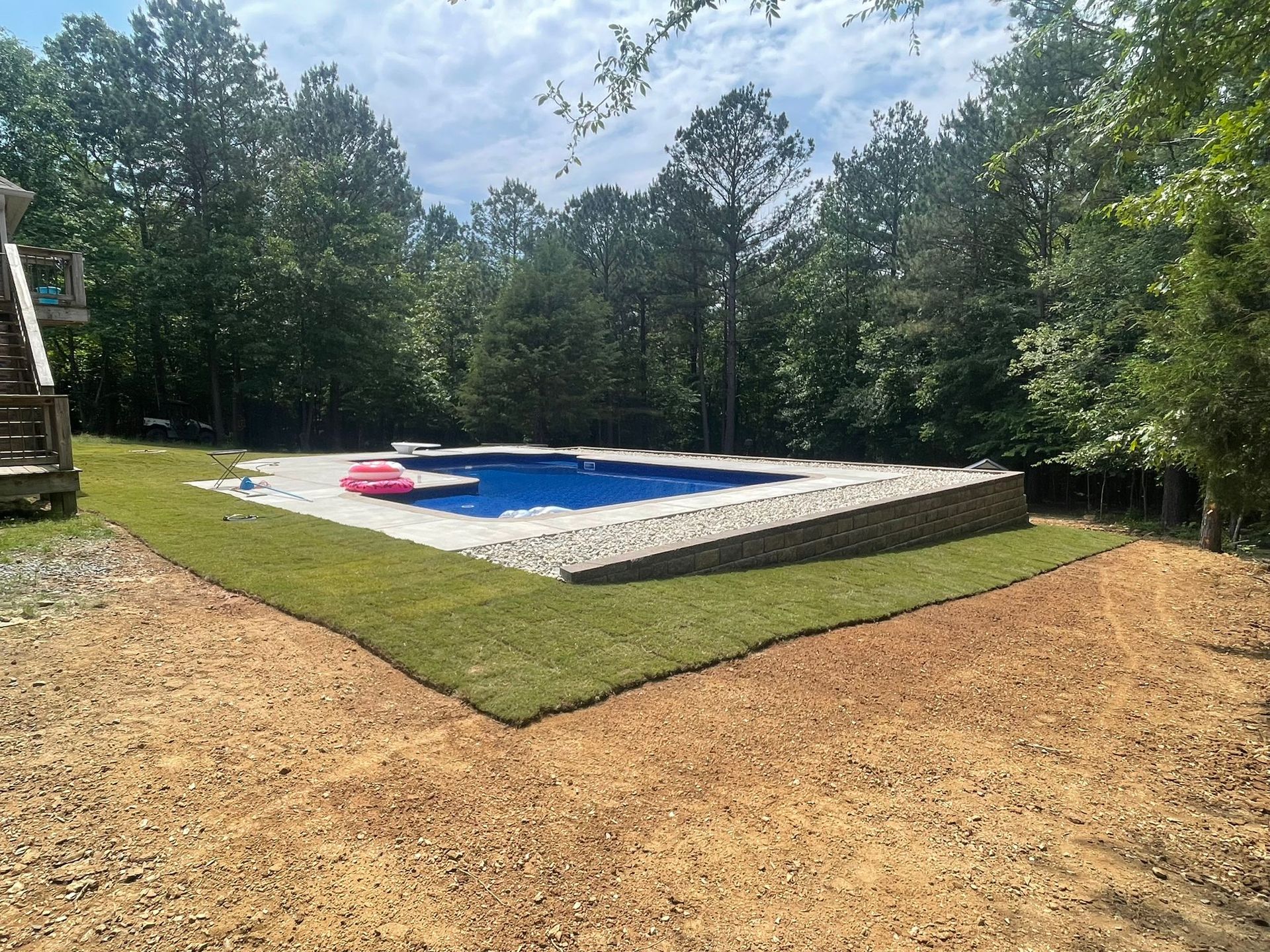 A large swimming pool in the middle of a lush green field surrounded by trees.