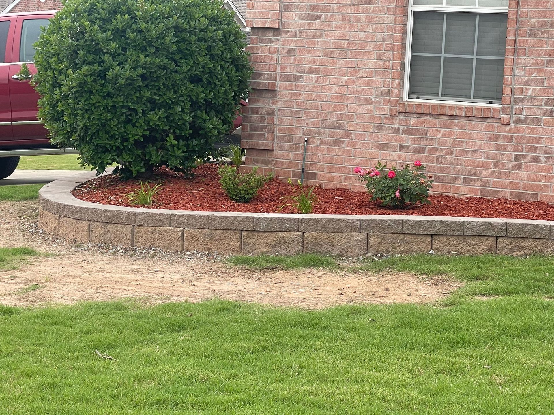 A red truck is parked in front of a brick house.