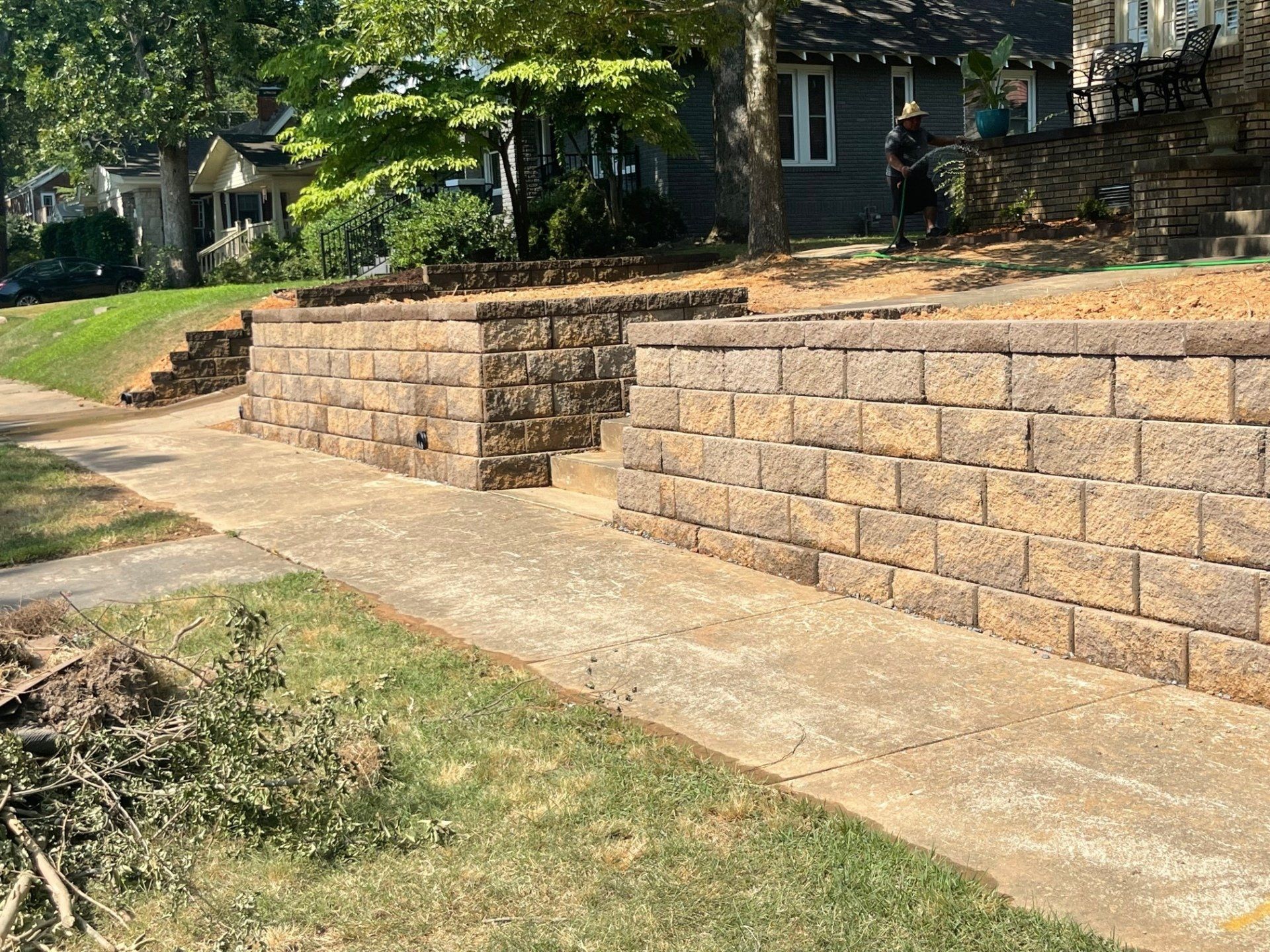 A brick wall along a sidewalk next to a house.