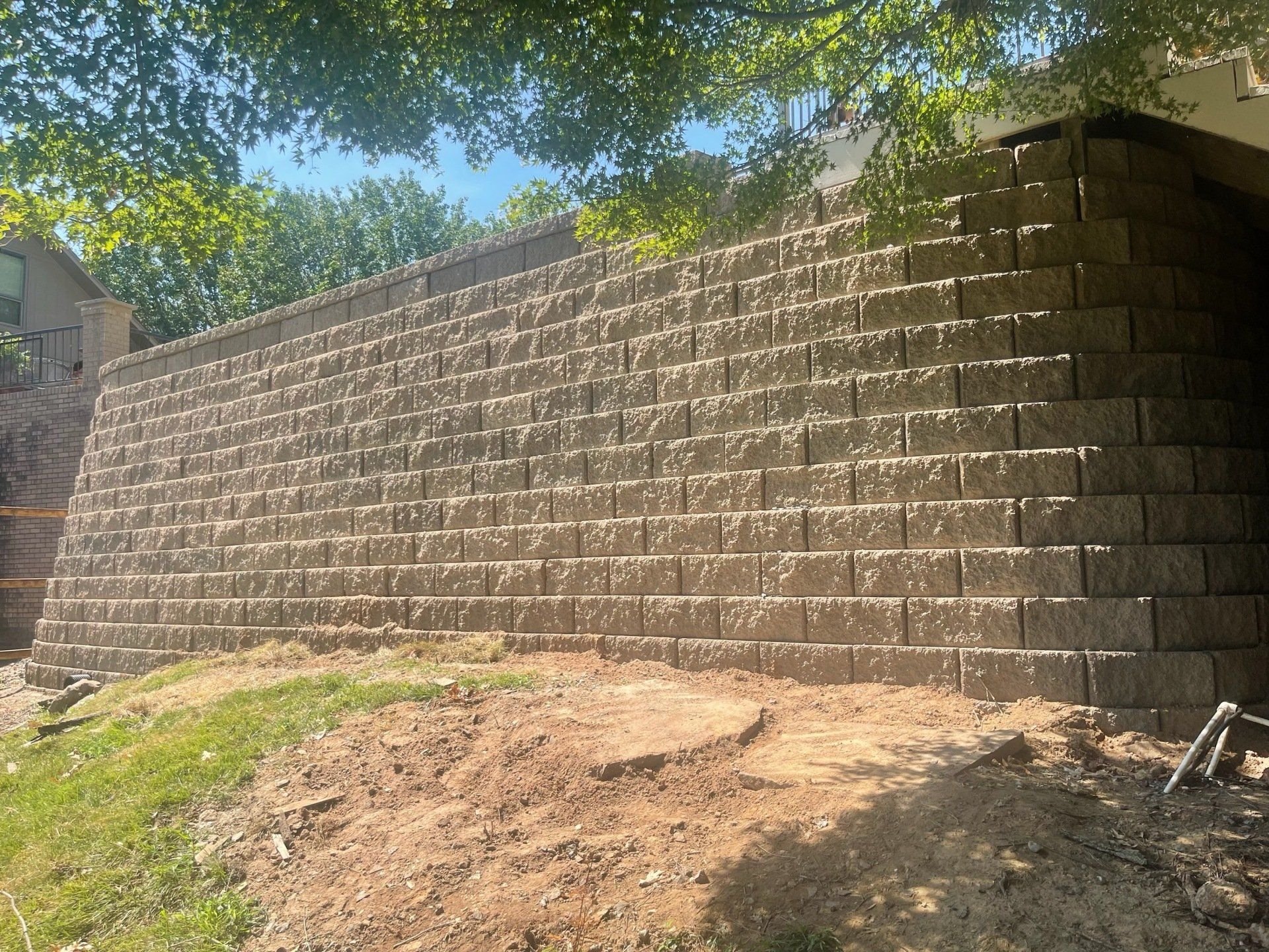 A large brick wall is sitting on top of a dirt hill.