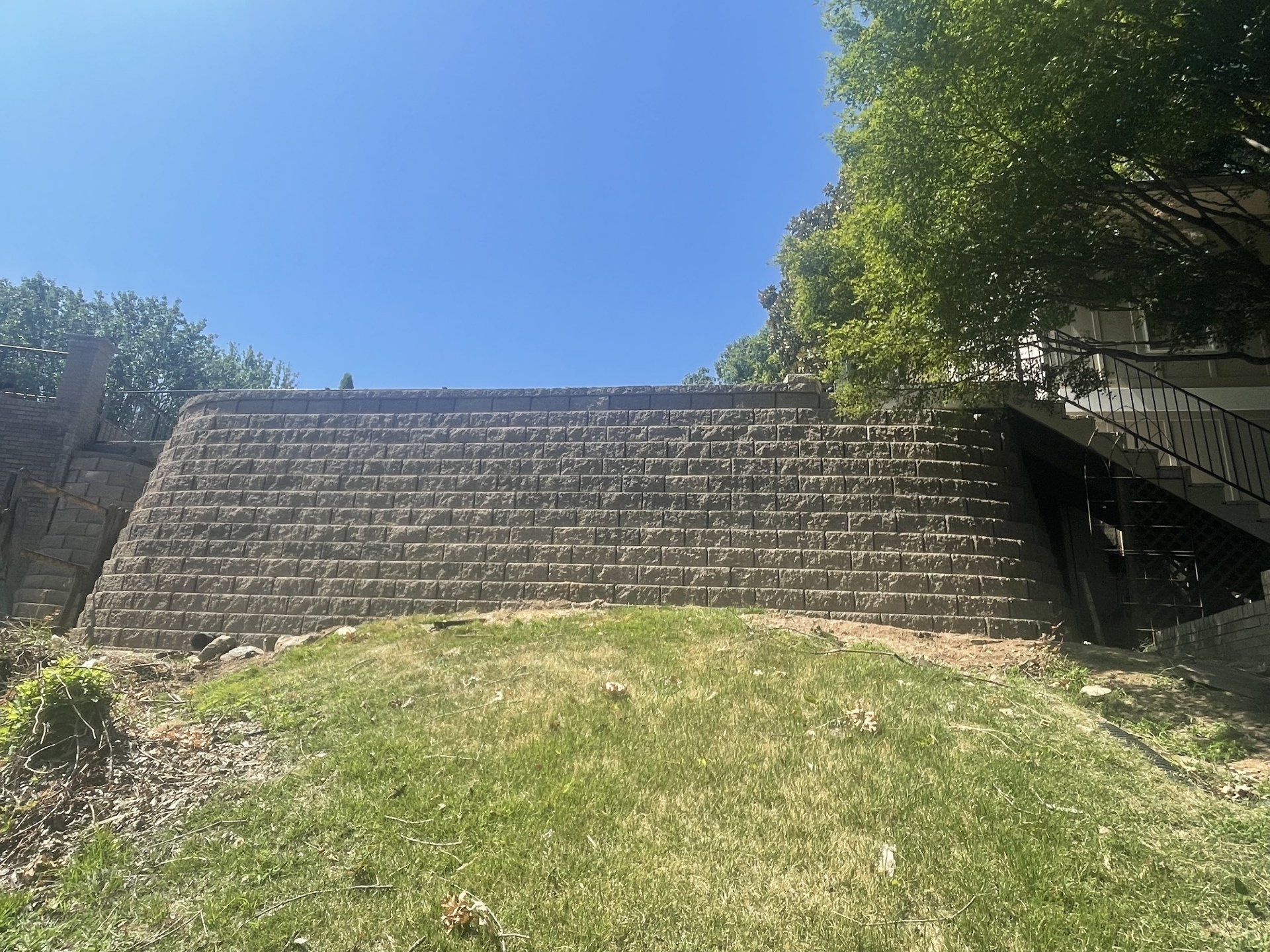 A large brick wall is sitting on top of a grassy hill.