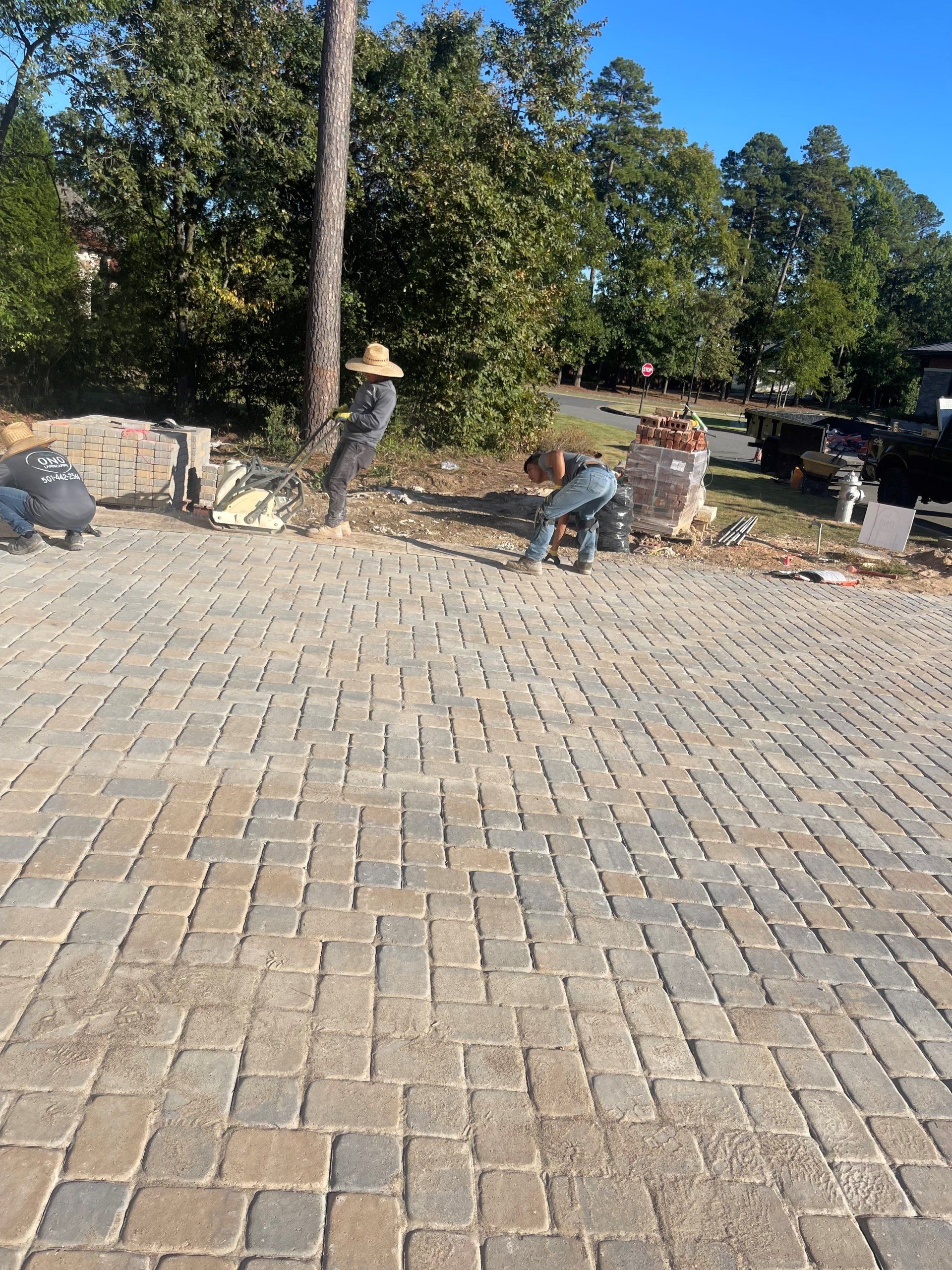 A group of people are working on a brick driveway.