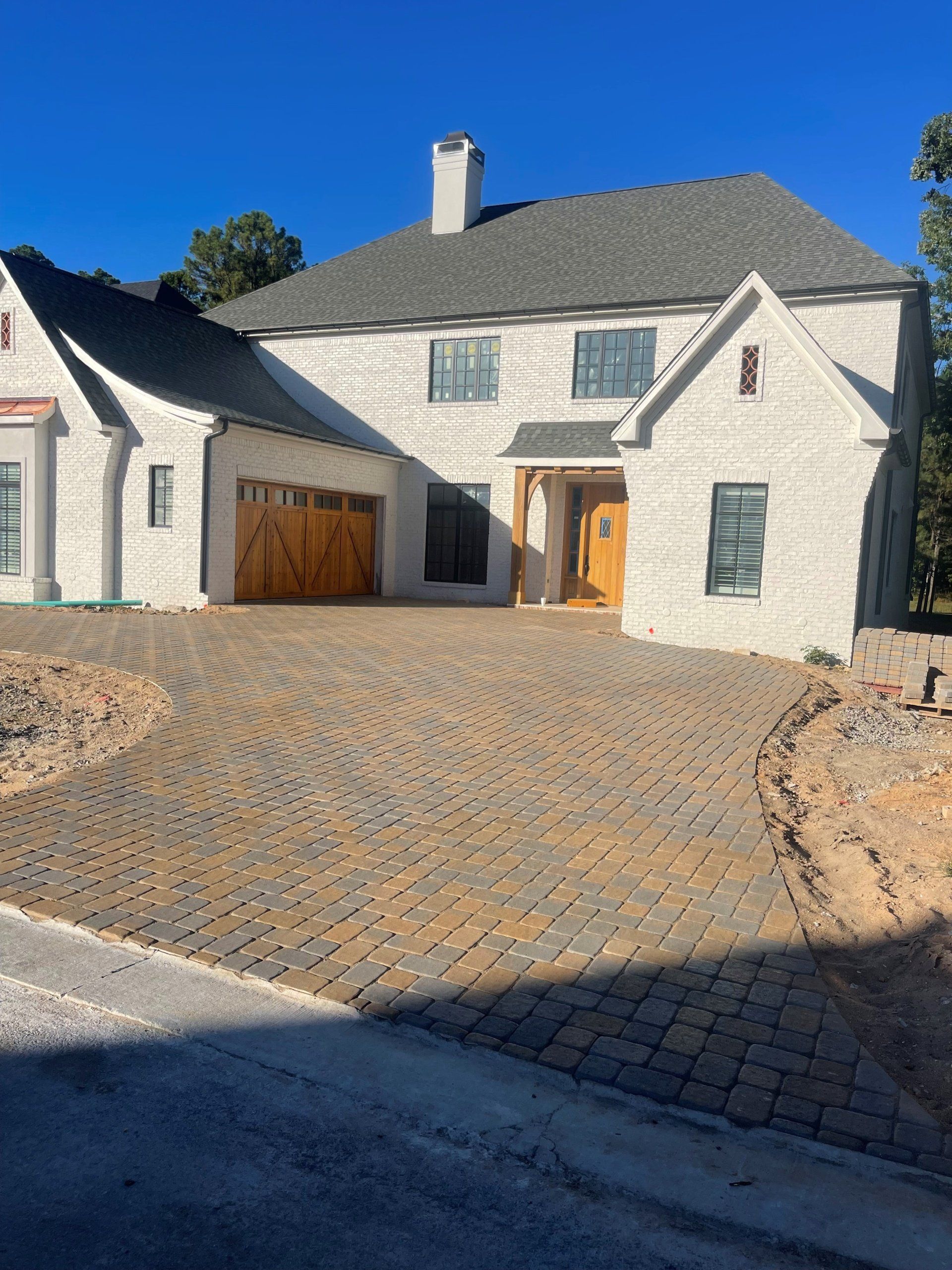 A large white house with a brick driveway in front of it