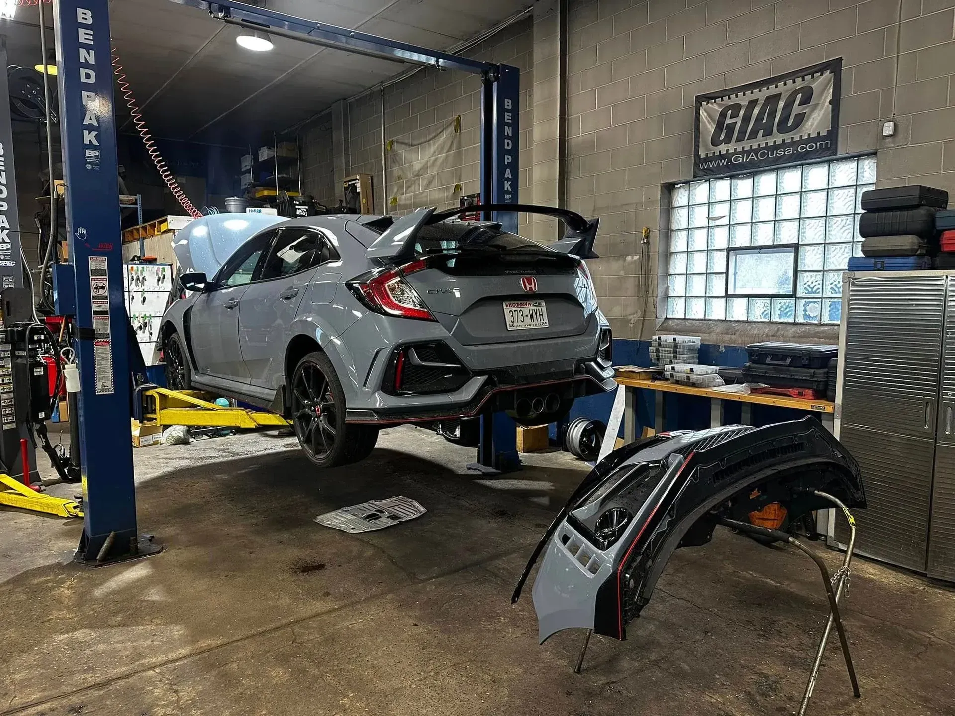 Honda Civic Type R on a lift in a garage, bumper removed.