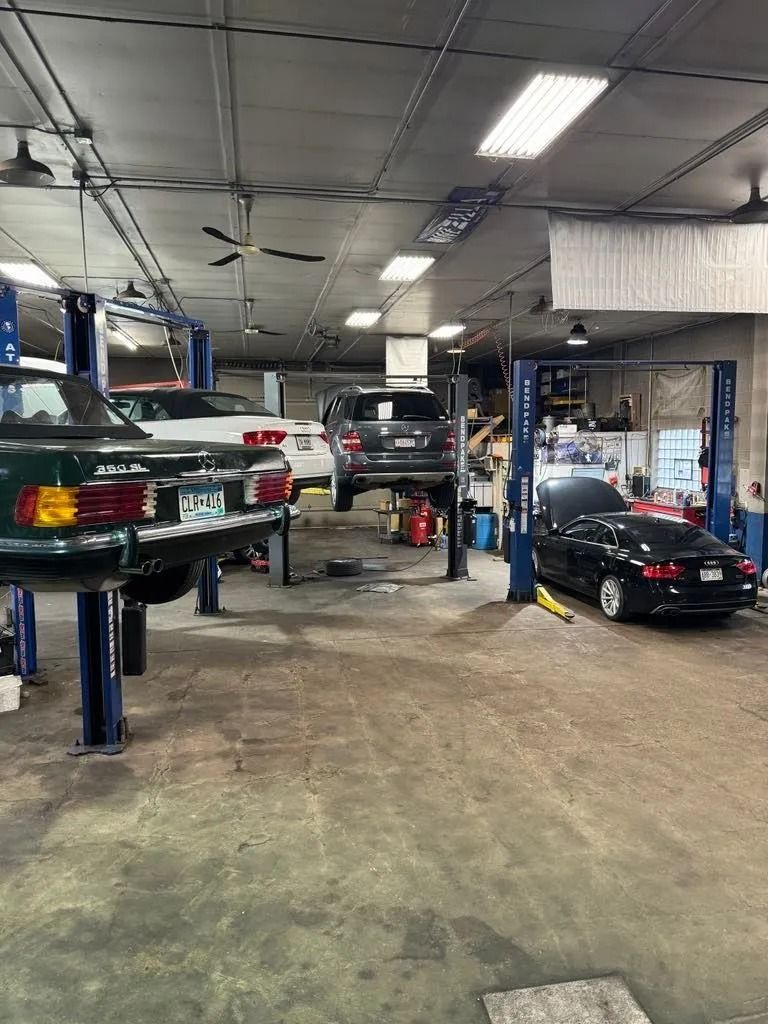 Auto repair shop with several cars on lifts; a Mercedes is in the foreground.