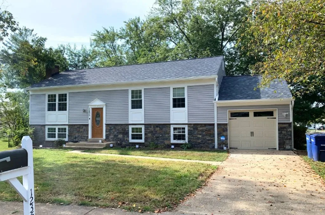 Gray house with blue roof and beige garage door; driveway and yard.