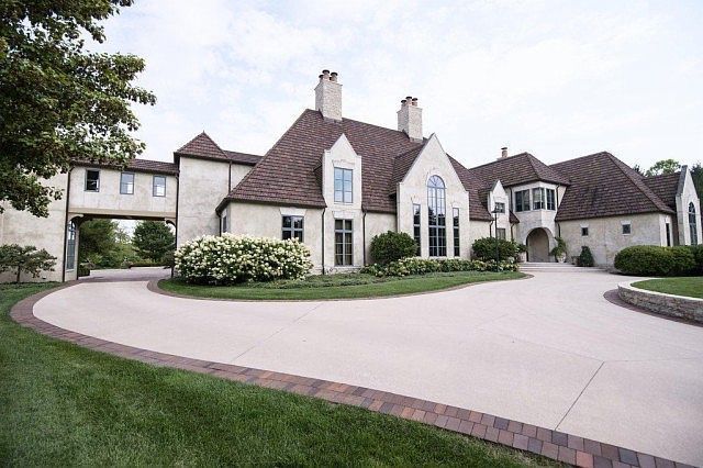 A large white house with a brick driveway leading to it.