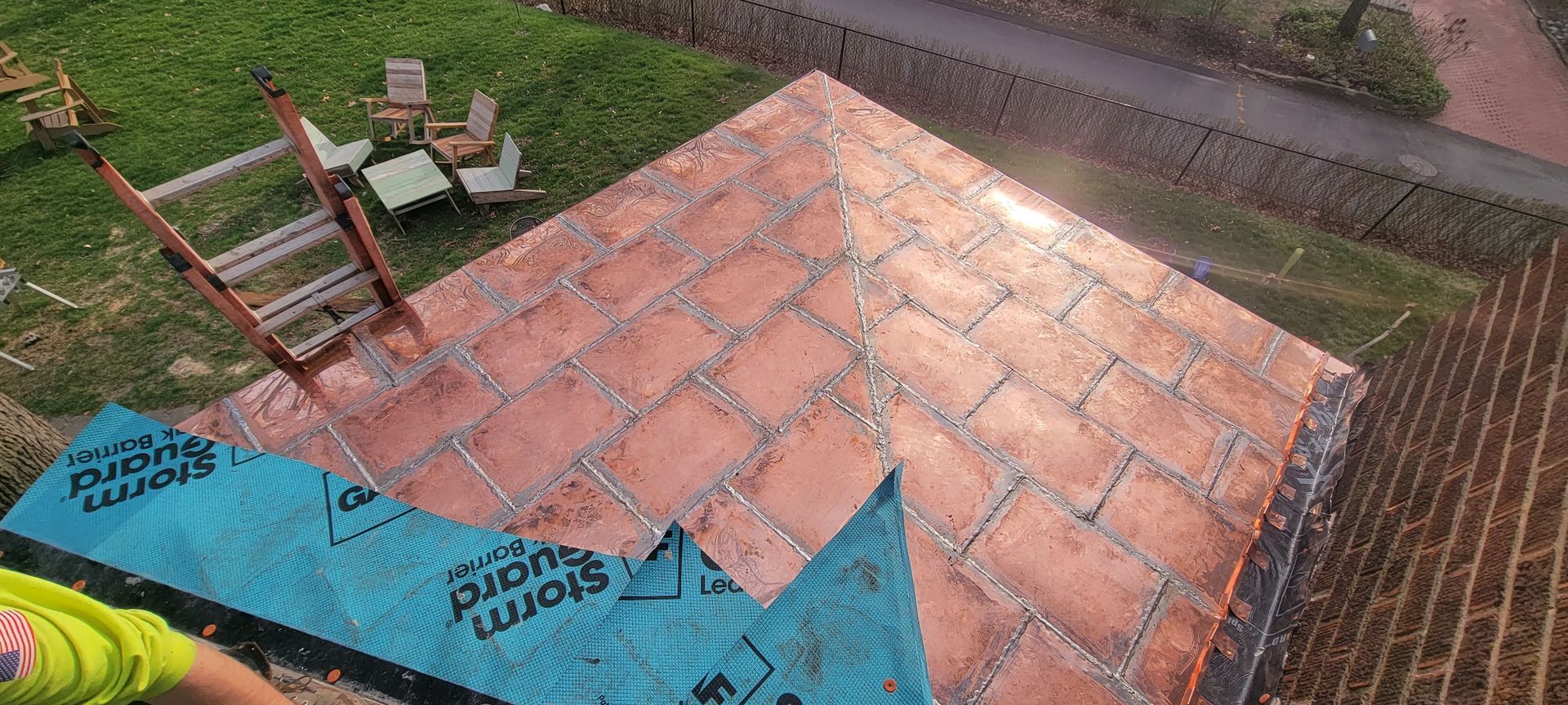 A person is standing on top of a brick patio with a ladder.