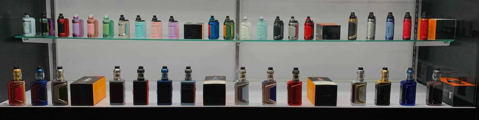 A display shelf in a shop featuring a wide selection of colorful vape devices and electronic cigarette mods.